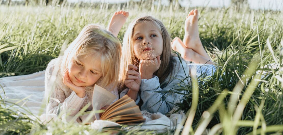 little girls lying on green grass field