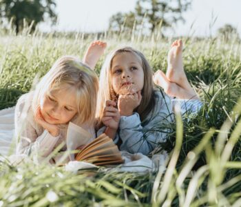 little girls lying on green grass field