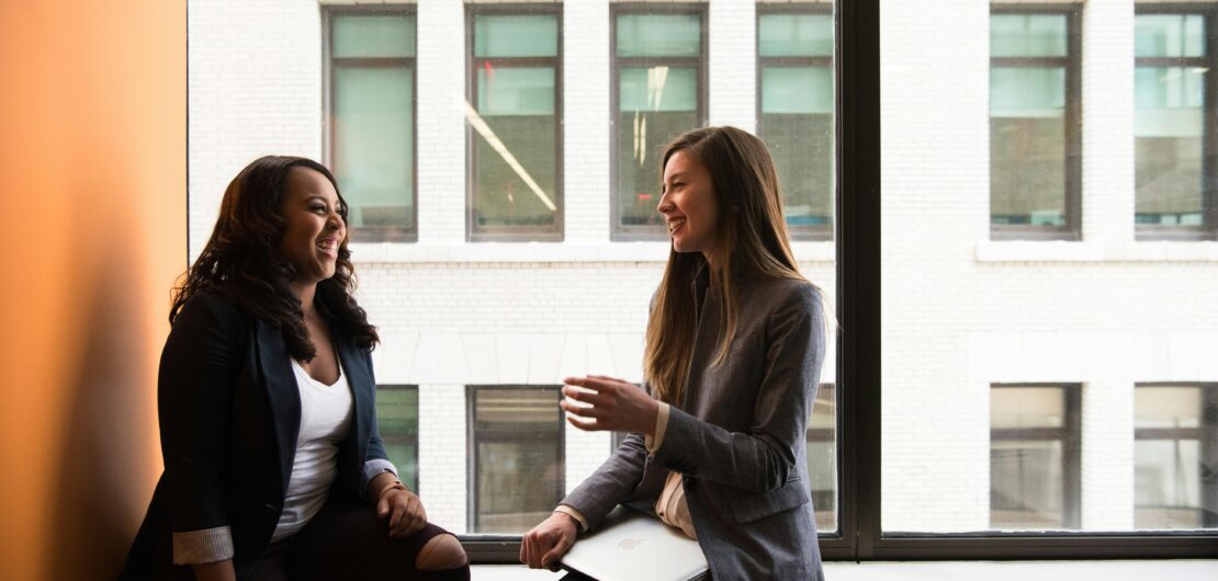 two women smiling and talking at work